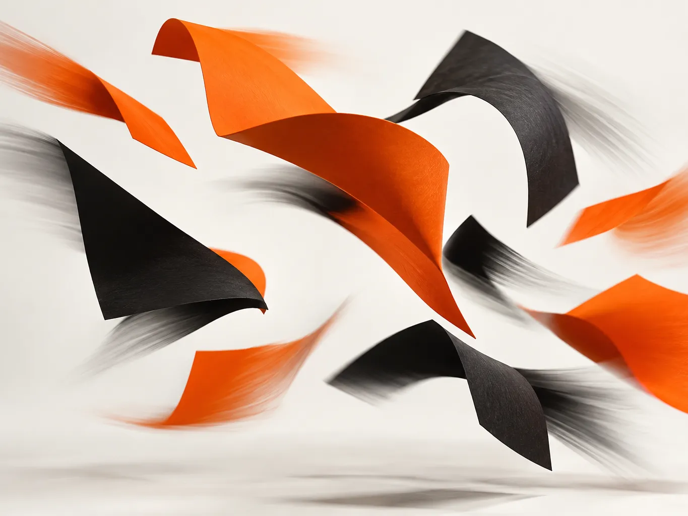 Abstract motion-blur photograph of bold orange and black paper shapes caught mid-air against an off-white backdrop,…