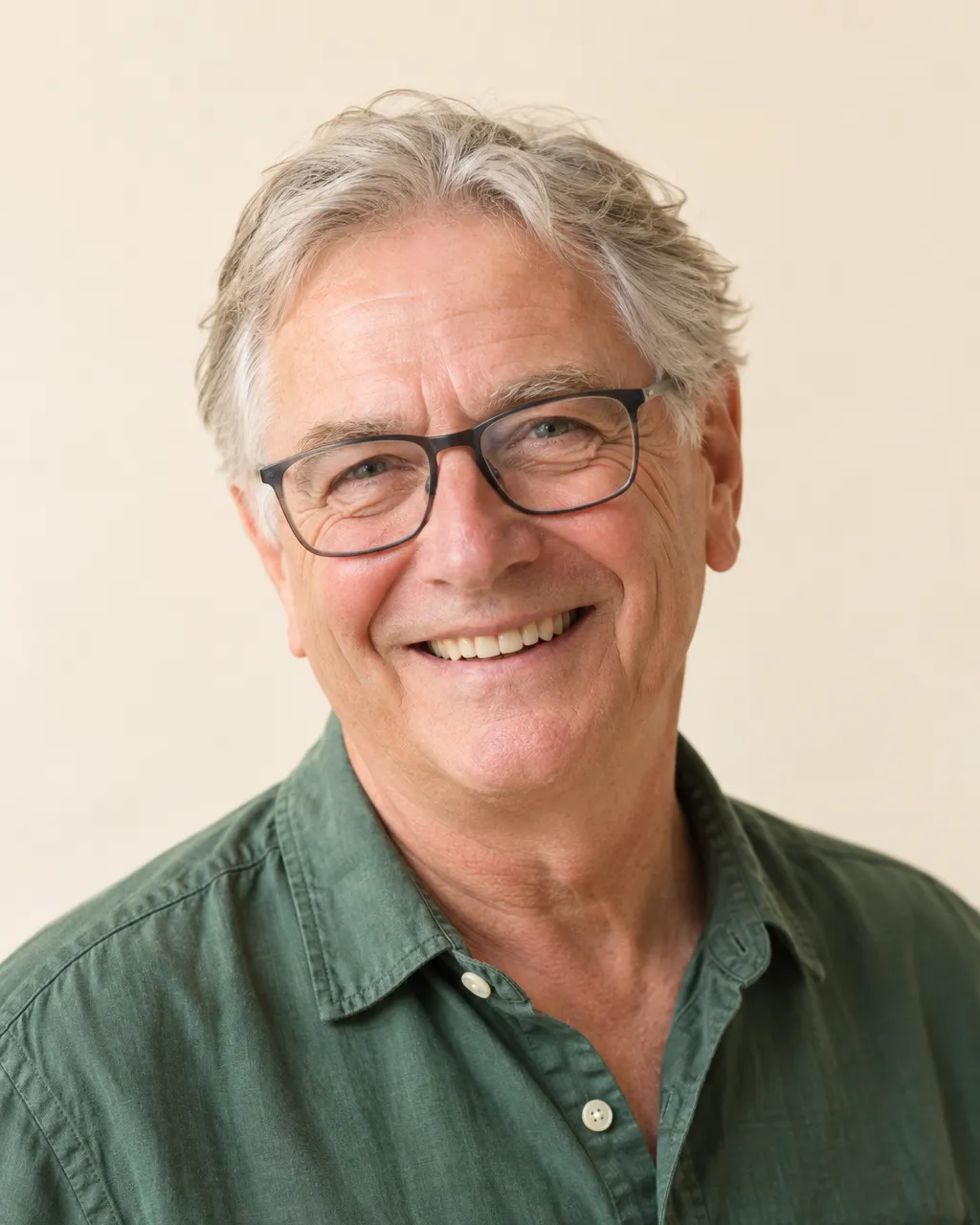 Studio-style team portrait of a cheerful white man in his late sixties with grey hair and glasses, volunteer lead,…