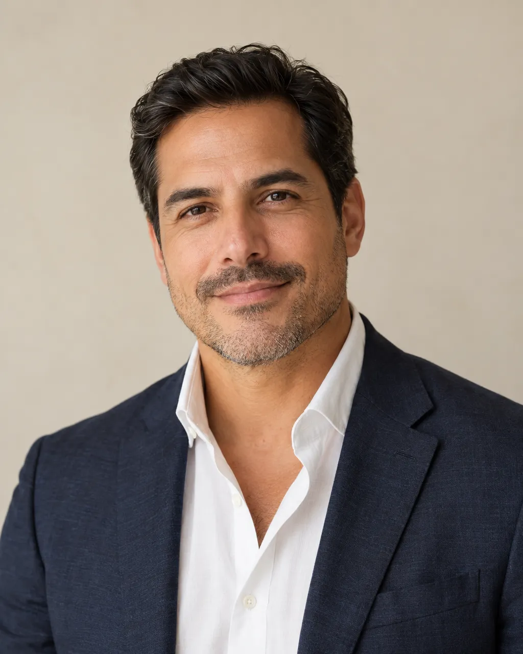 Professional portrait of a Latino man real estate partner in his forties with short dark hair and light stubble,…