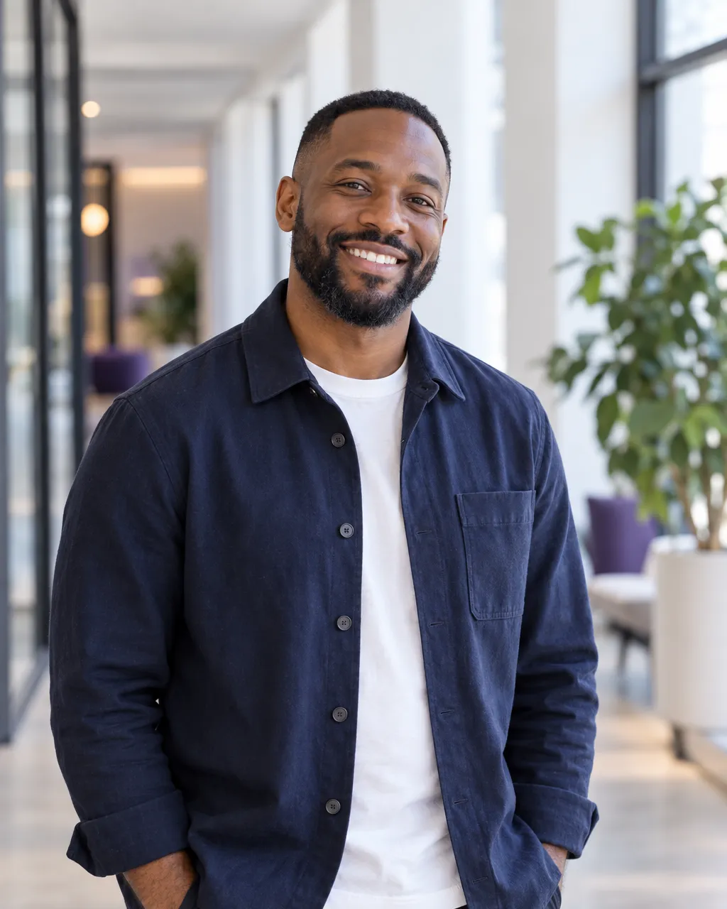 Environmental portrait of a Black man in his mid-thirties, director of revenue operations, wearing a navy overshirt,…