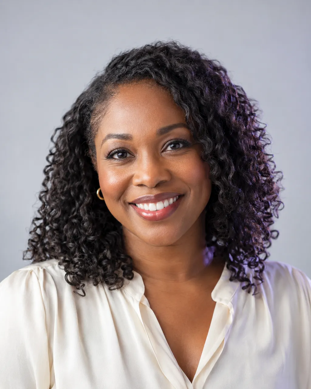 Professional head-and-shoulders portrait of a Nigerian-American woman in her late thirties with natural…