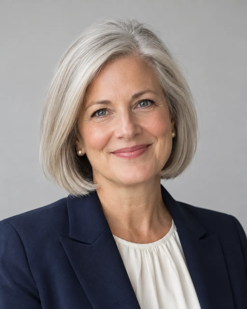 Professional portrait of a white woman in her fifties, head of school, silver bob, navy blazer over a cream blouse